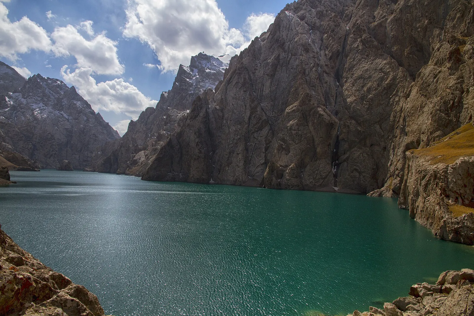 Turquoise water of Kel-Suu Lake between steep rock walls